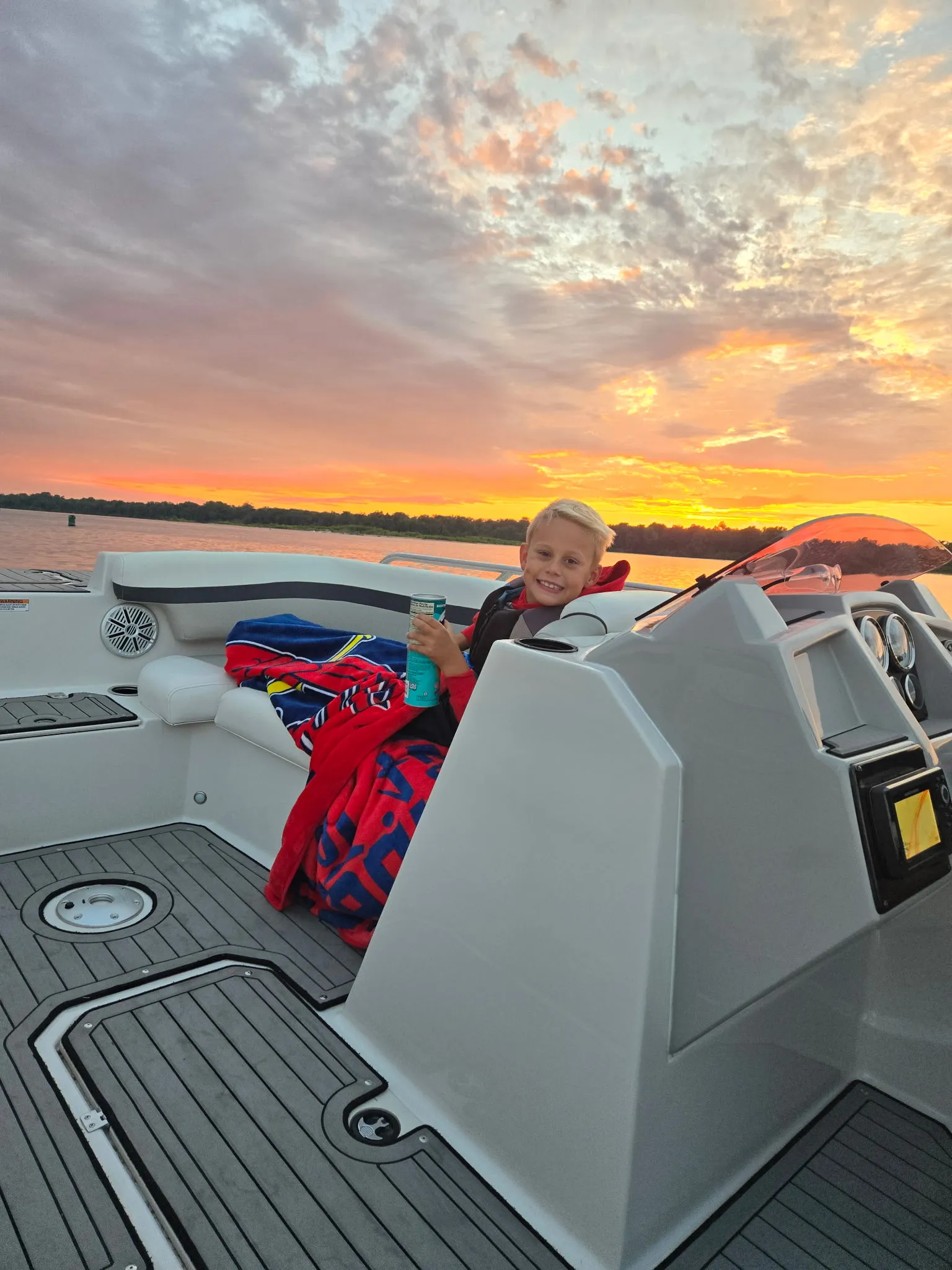 Jessica Zerr's son Cameron smiling on the family boat at sunset on the Mississippi River