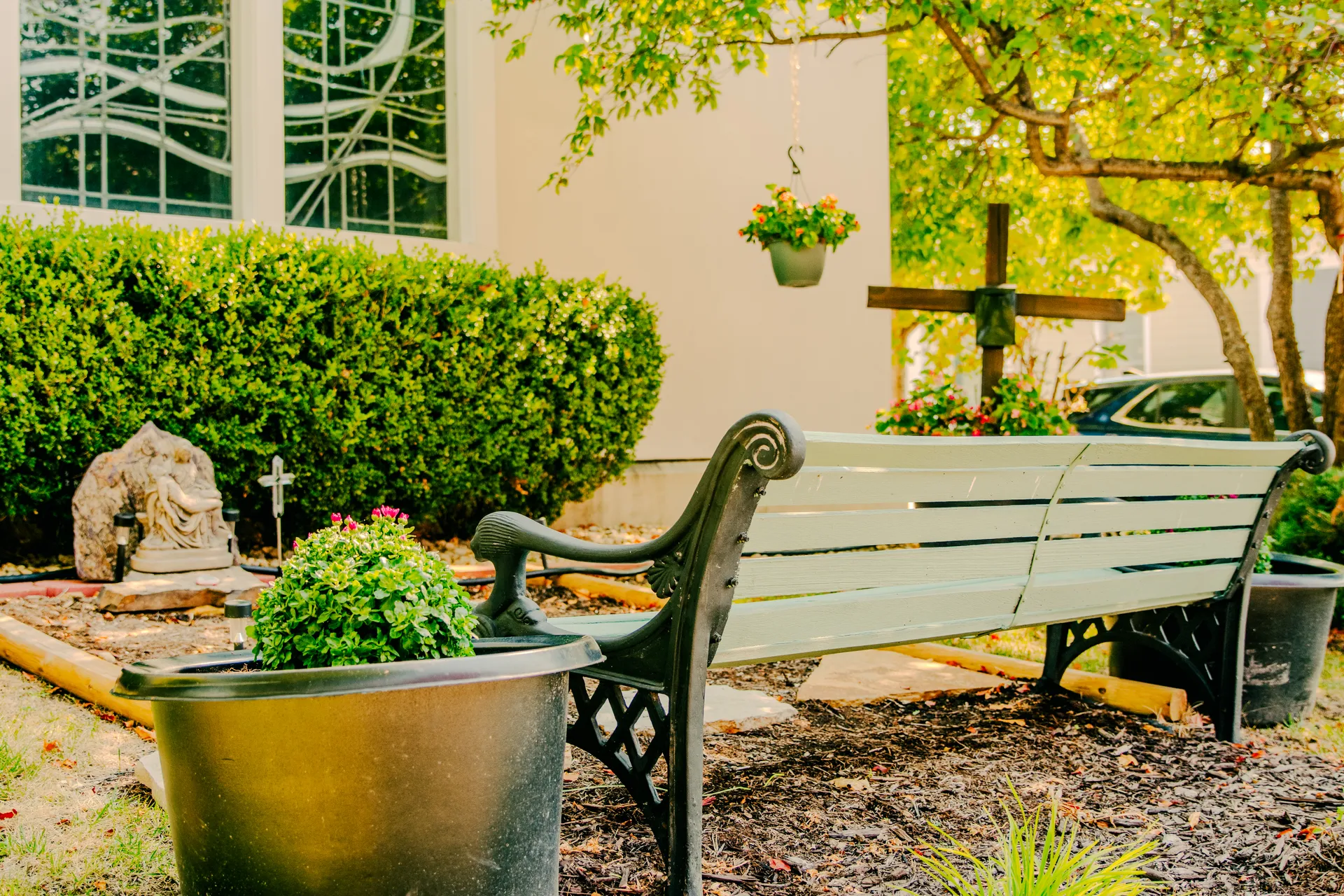Garden bench, Pietà statue and wooden cross in the Serenity Garden
