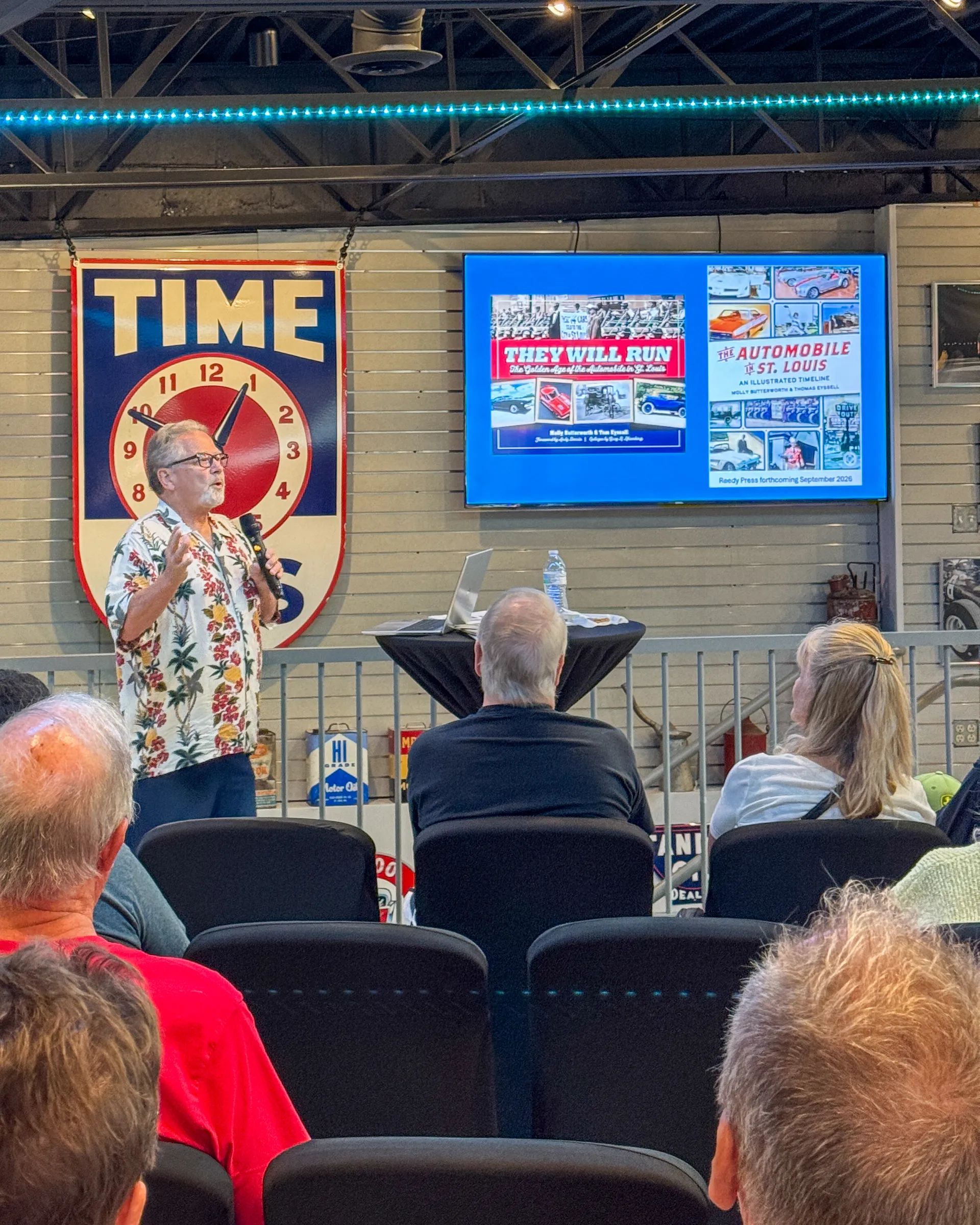Tom Eyssell presenting slides of his books, including They Will Run, to the audience at Fast Lane Classic Cars
