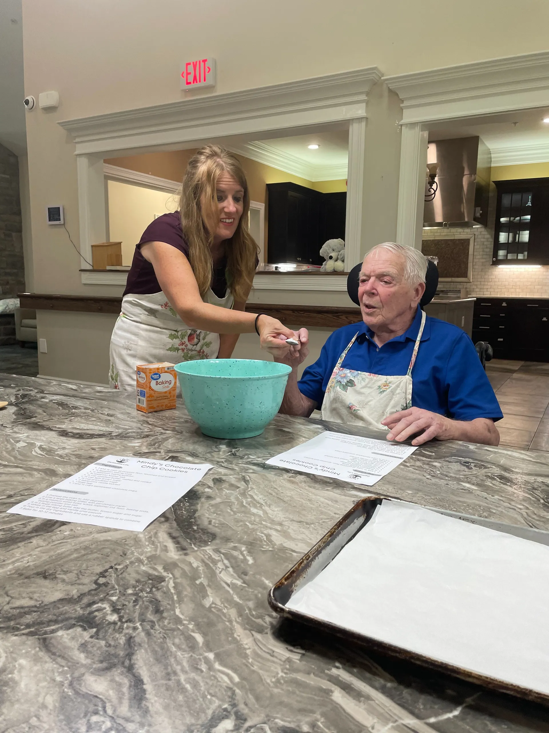 A Dementia Life volunteer helps a resident bake chocolate chip cookies in a community kitchen
