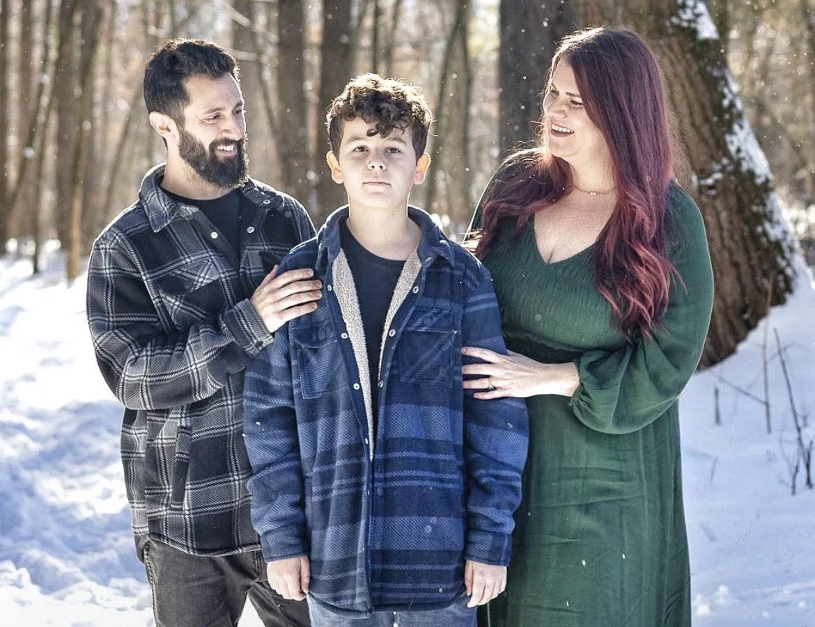 Lindsay Sutton with her husband and son in a snowy woodland