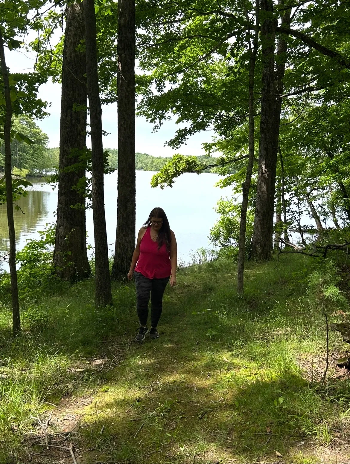 Lindsay Sutton hiking a wooded trail beside a lake