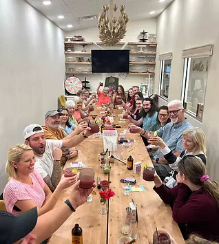 Guests raising cocktails at a long table during a Lydia's Cocktail Club gathering