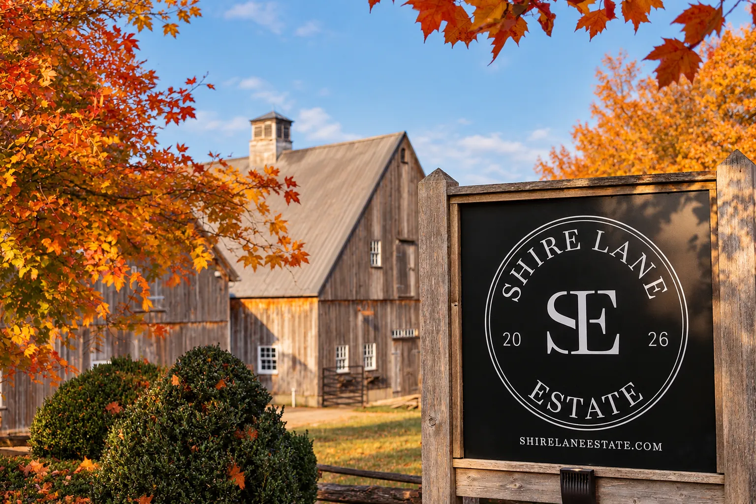 Shire Lane Estate sign in front of the rustic barn framed by autumn maple leaves