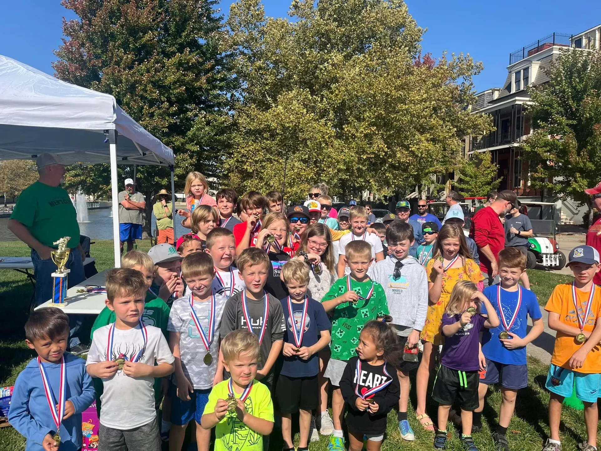 Kids show off their medals and a trophy after the New Town Fishing Tournament