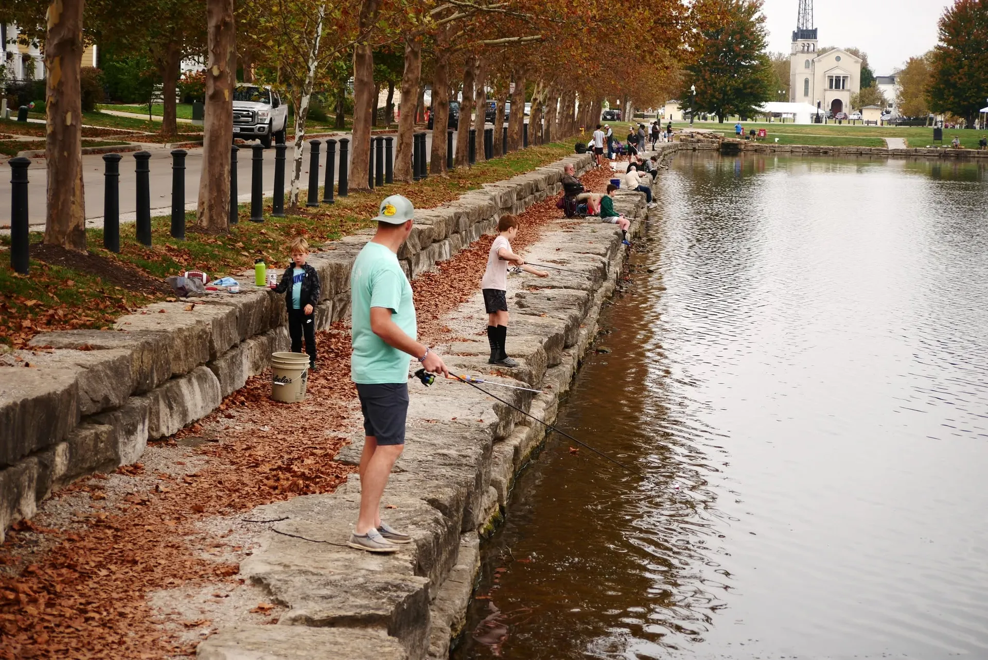 Families fishing along the stone edge of the Big Lake in New Town on a fall morning