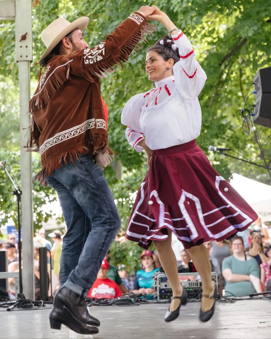 Two folk dancers in traditional costume performing on the New Town Amphitheater stage