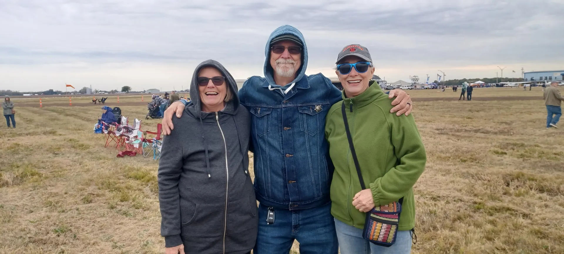 Three smiling spectators pose arm-in-arm on the field at Smartt Field during the Pumpkin Drop