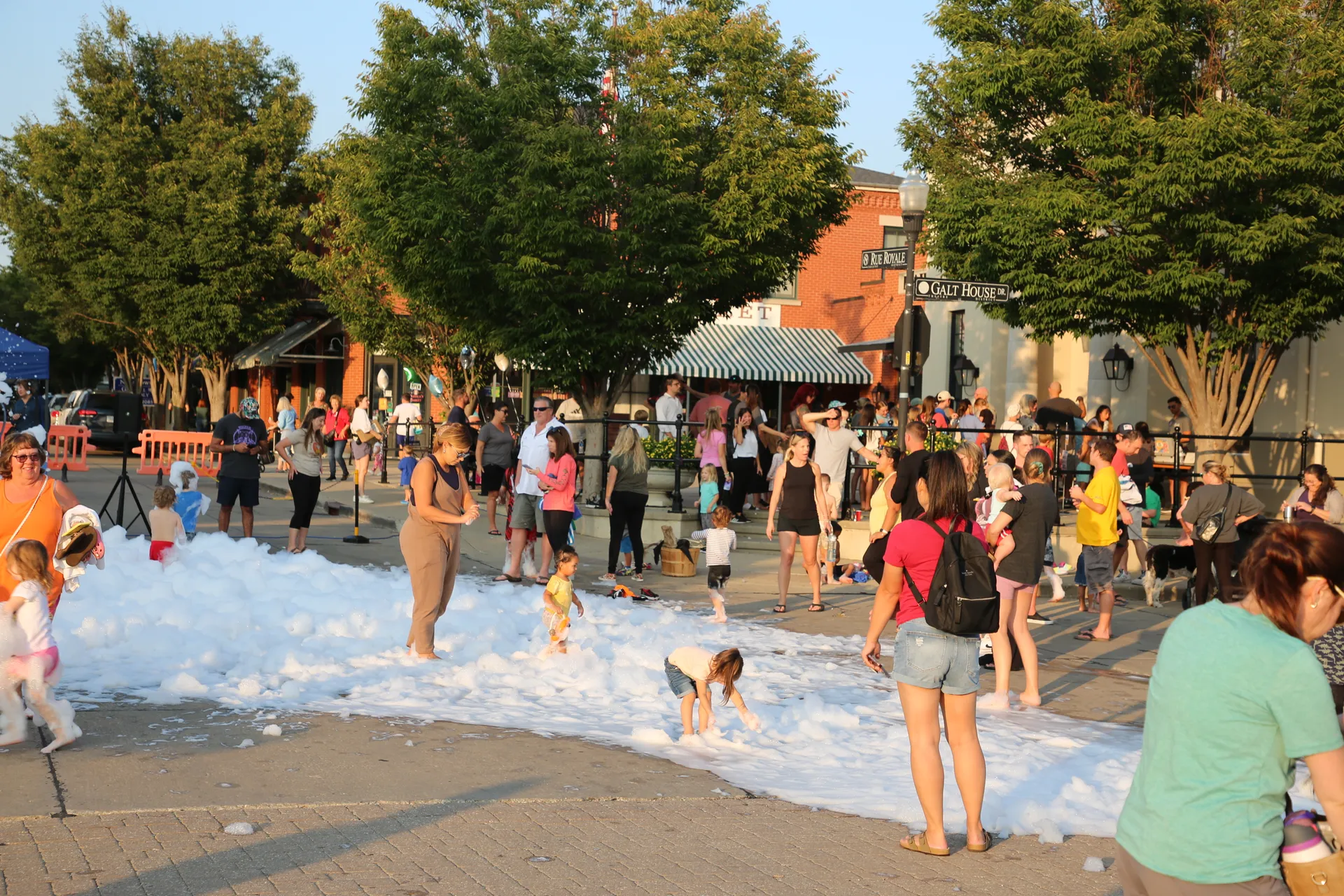 Neighbors gathered outdoors as children play in the foam at St. Charles Night Out