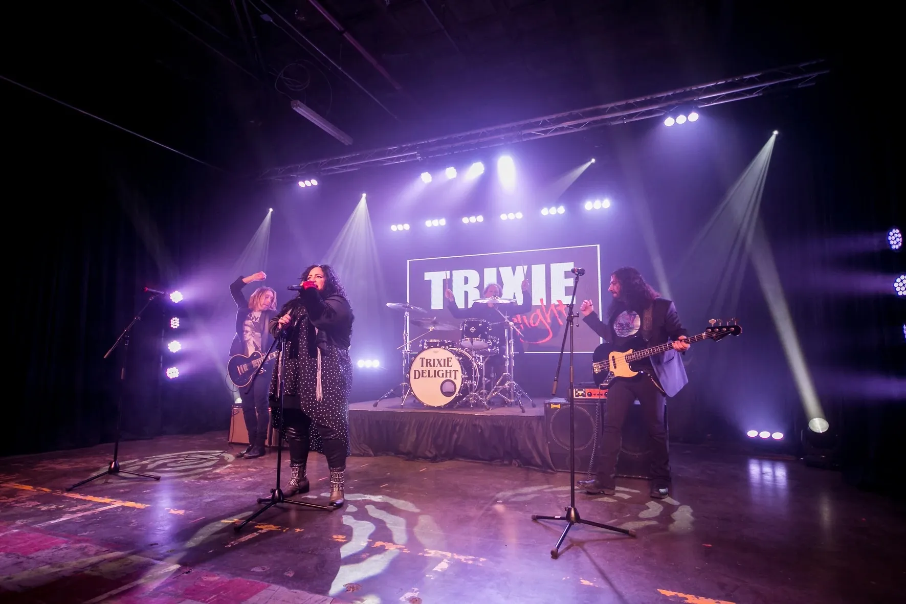Trixie Delight performing live on stage under purple lights
