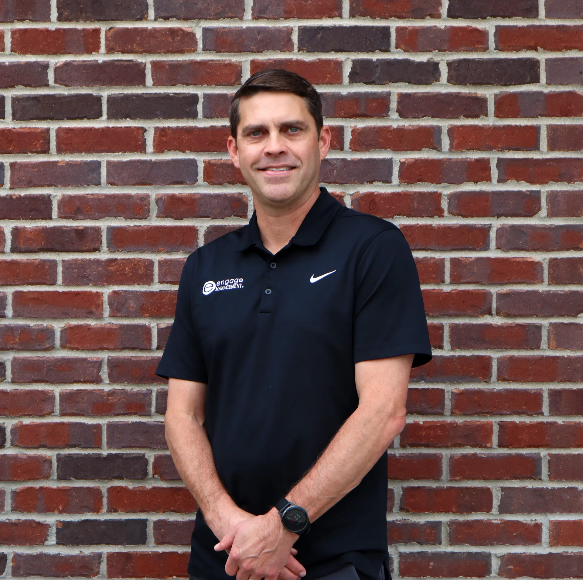 Brent Salter, President of Engage Management, in an Engage Management polo in front of a brick wall