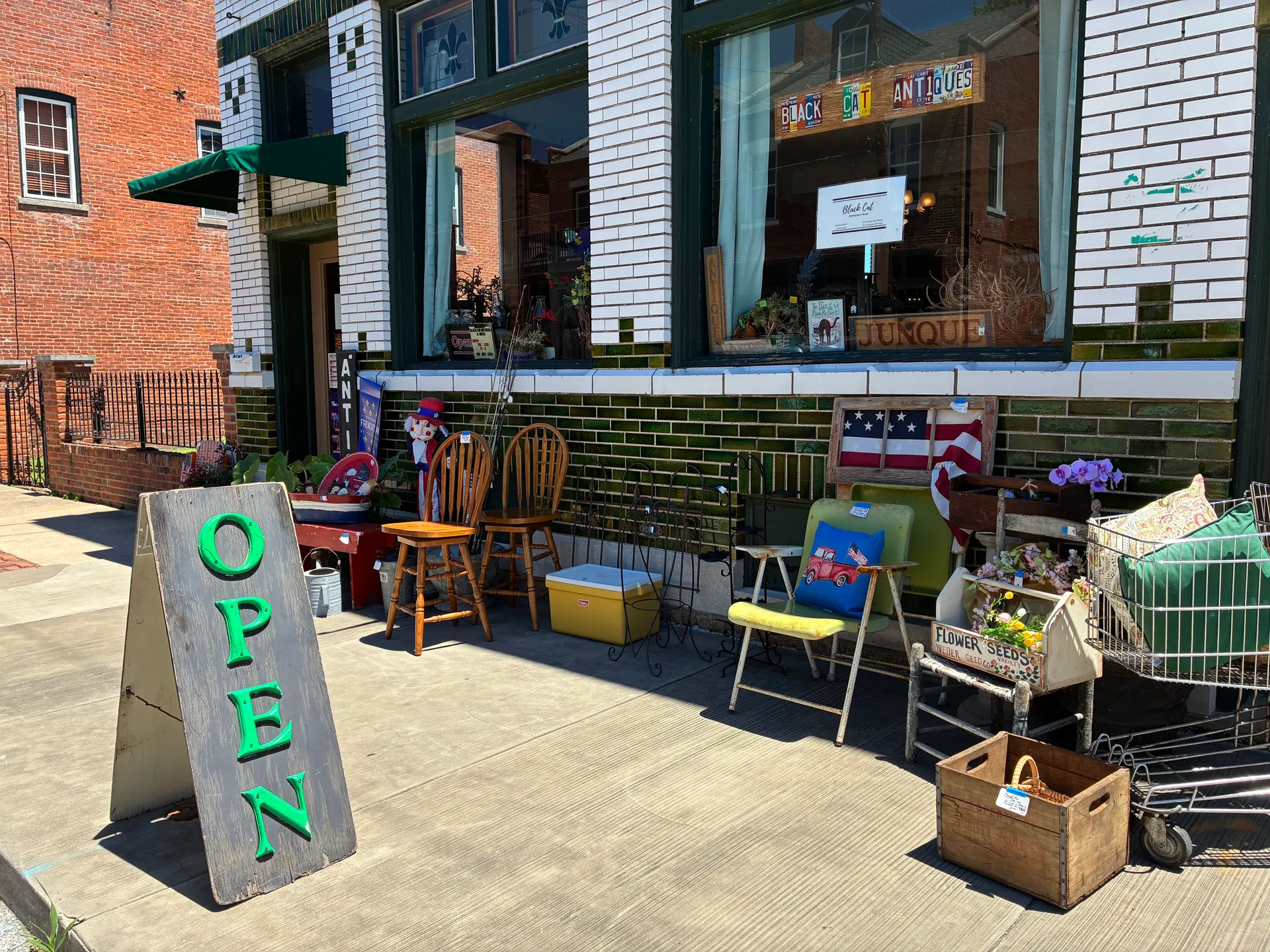 Storefront of Black Cat Antiques and Such on N. Second St. with an OPEN sign and vintage chairs on the sidewalk