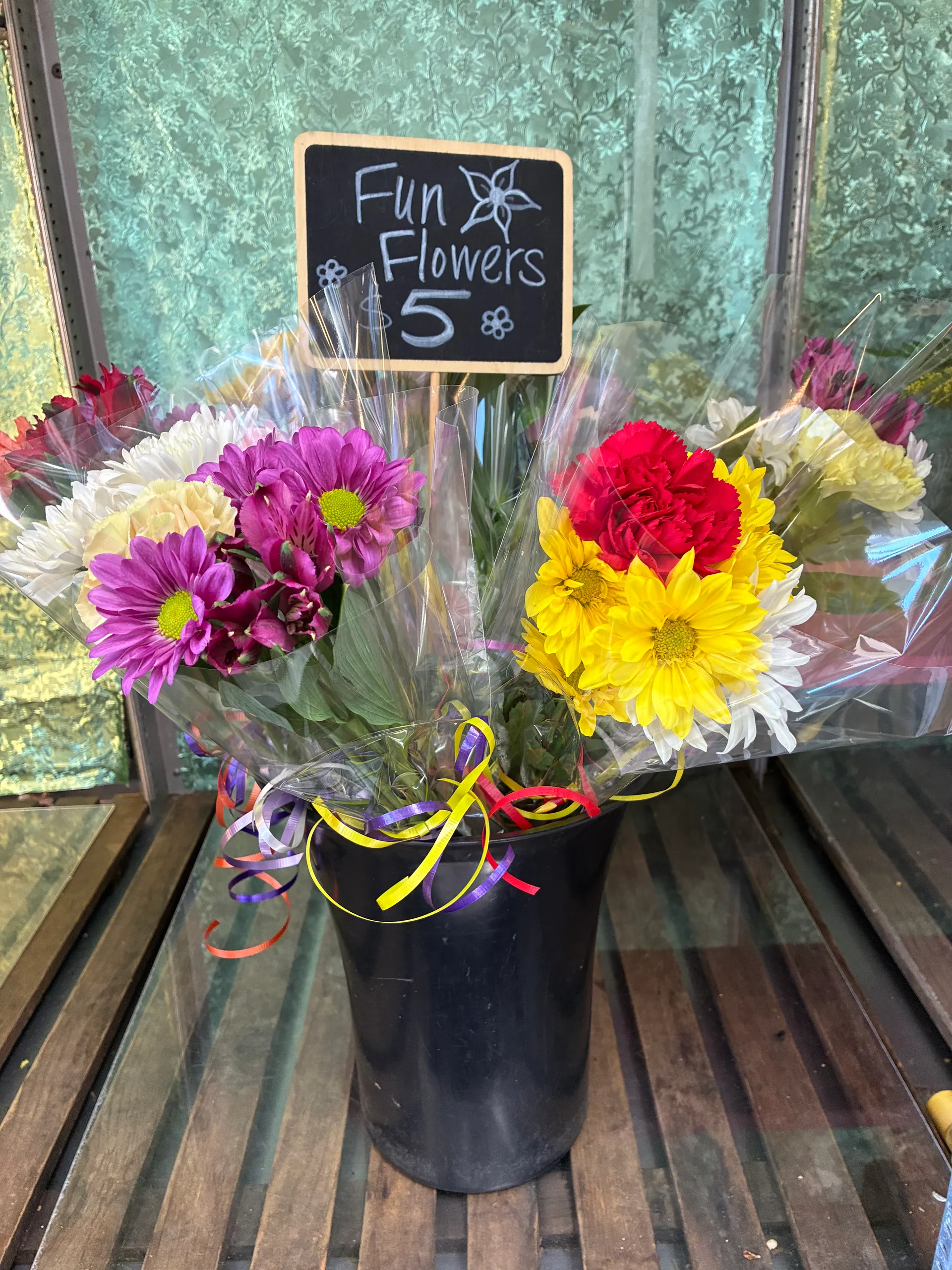 Bucket of wrapped $5 Fun Flowers bouquets with a chalkboard sign