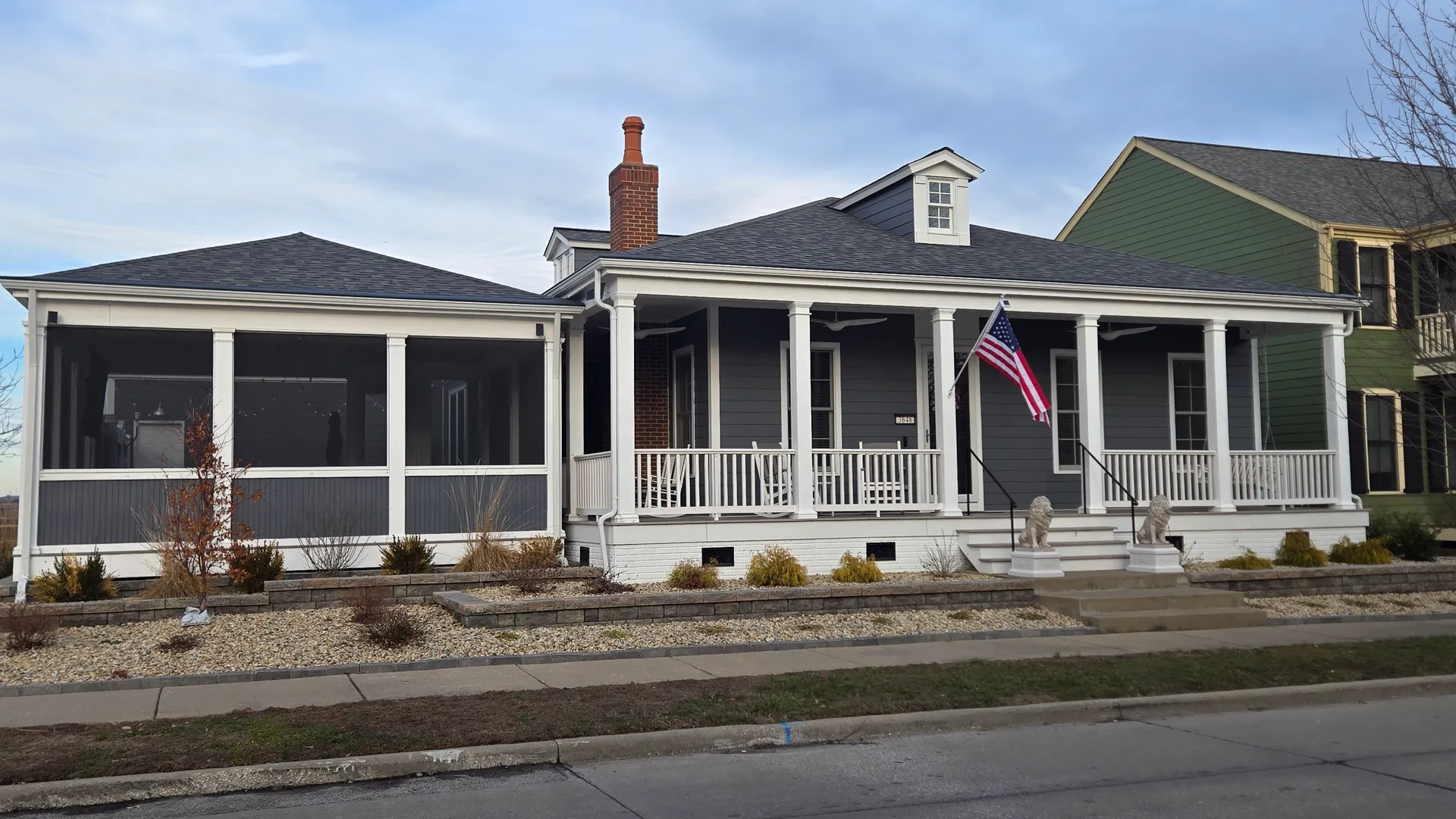 Gray New Town home with fresh siding, white porch columns and screened porch