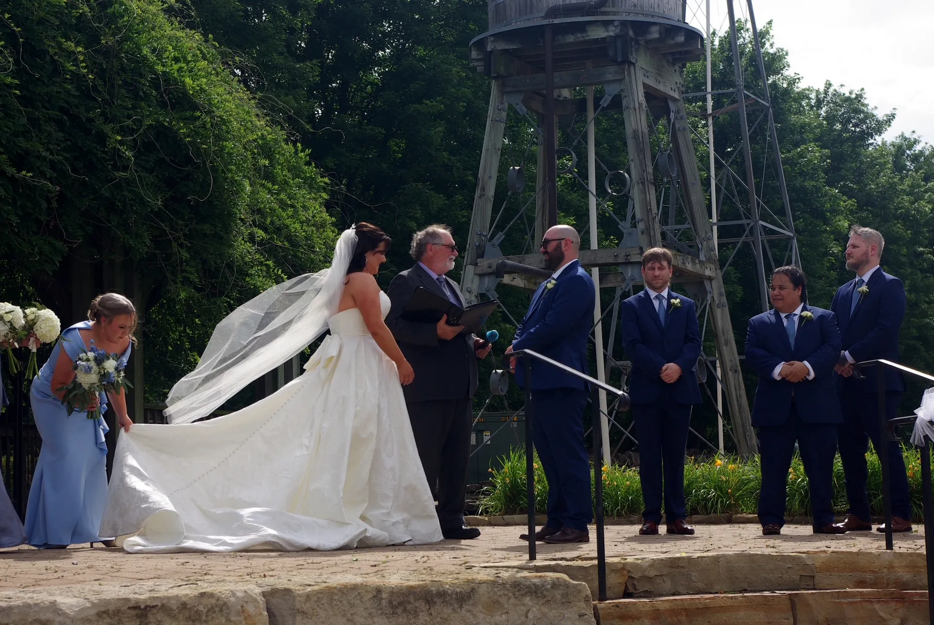 The bride and groom at the ceremony beside the rustic water tower at Shire Lane Estates