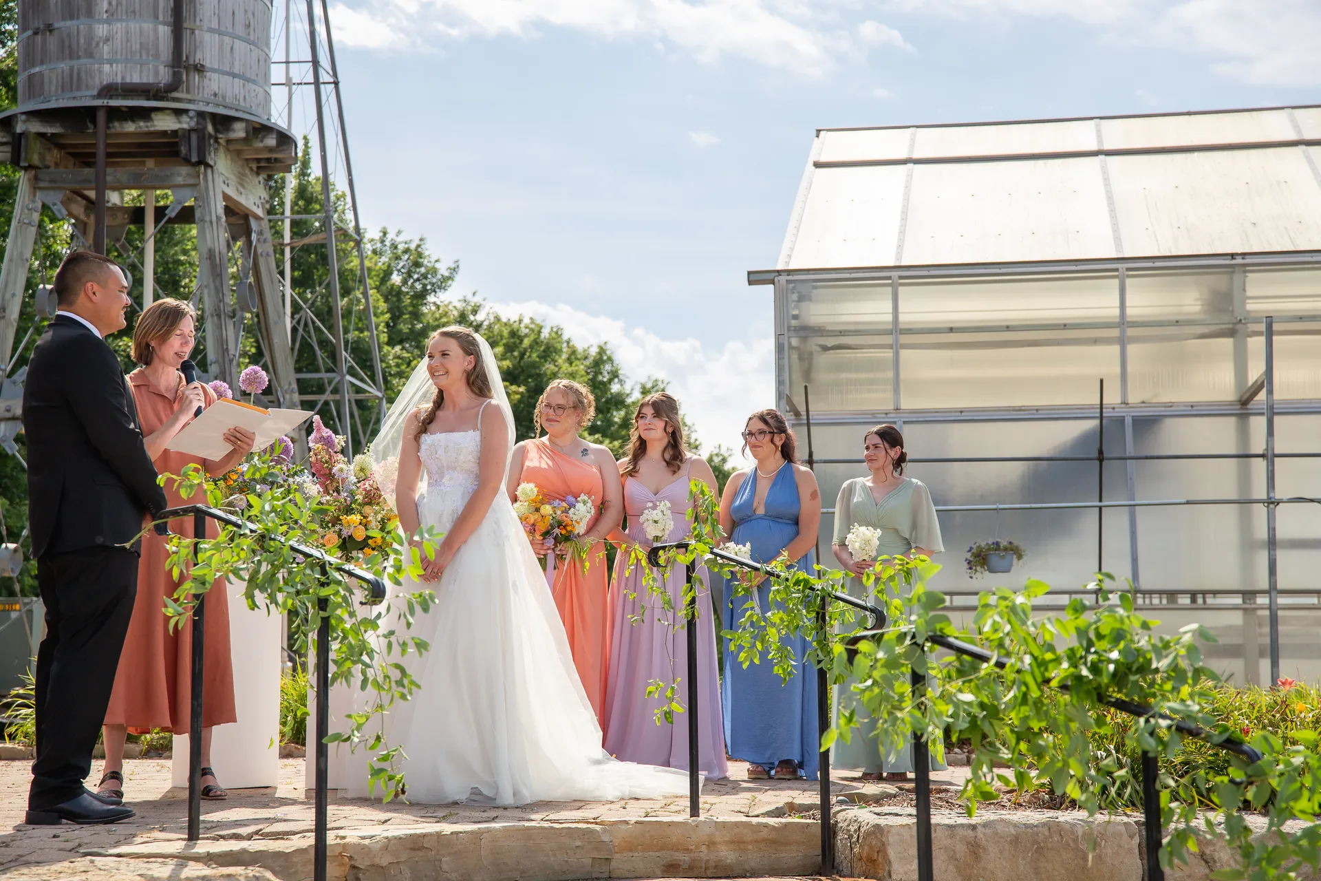 Kacey and her bridesmaids in pastel dresses during the outdoor ceremony beneath the water tower