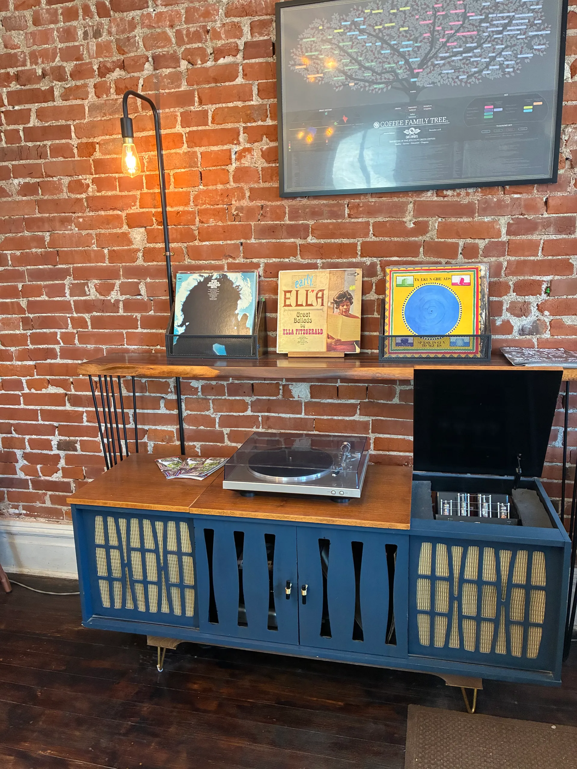 Vintage stereo cabinet with a working turntable and classic vinyl records against the exposed brick wall