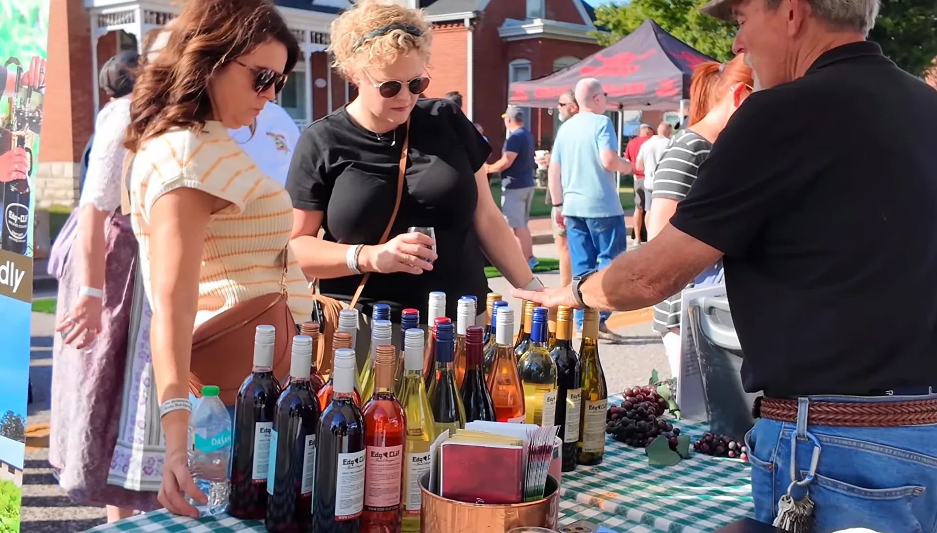 Festivalgoers browse bottles of local wine at a vendor table during the St. Charles Wine Festival in Historic Frenchtown