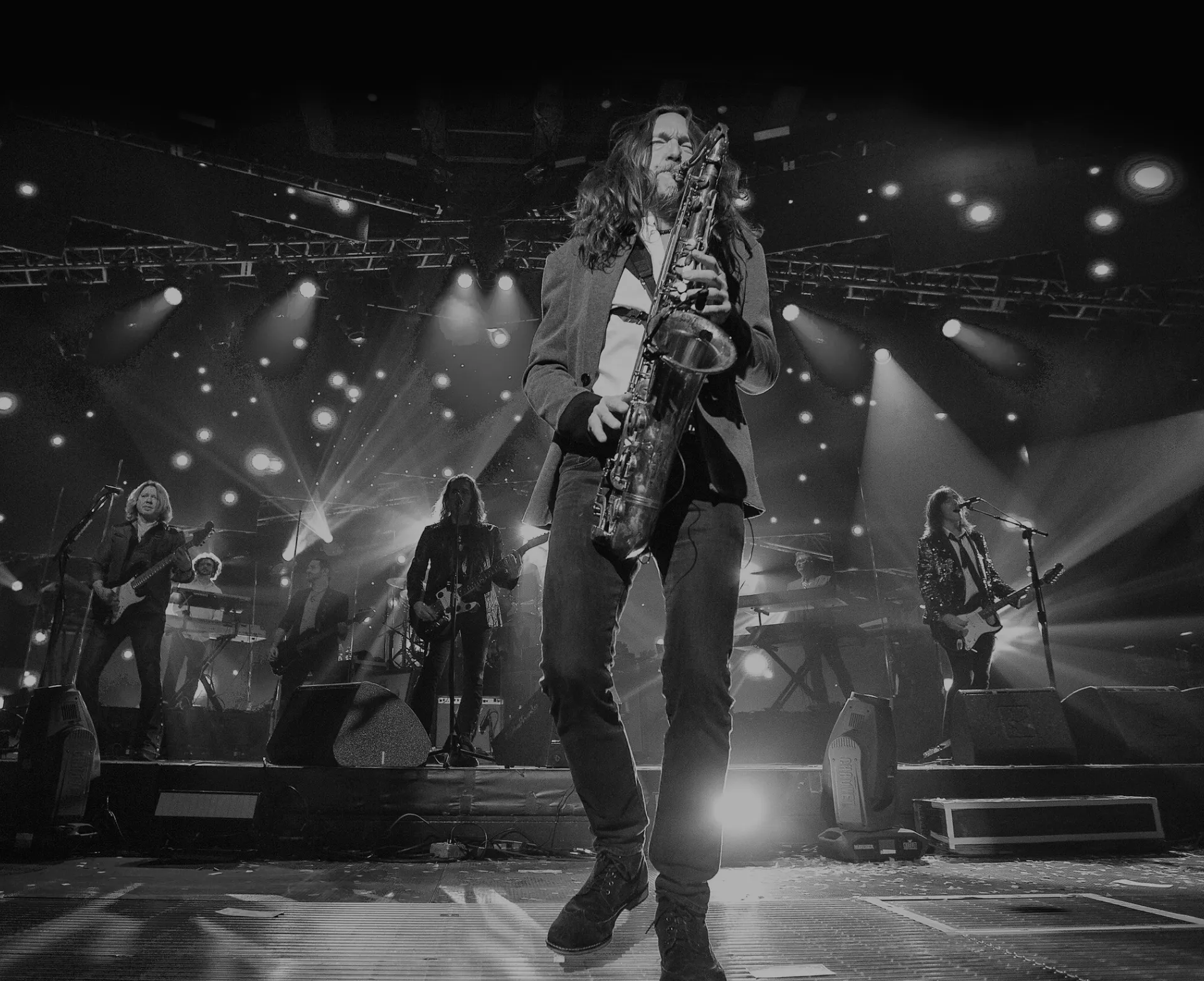 Black-and-white photo of Dave Farver playing saxophone on stage with the band behind him