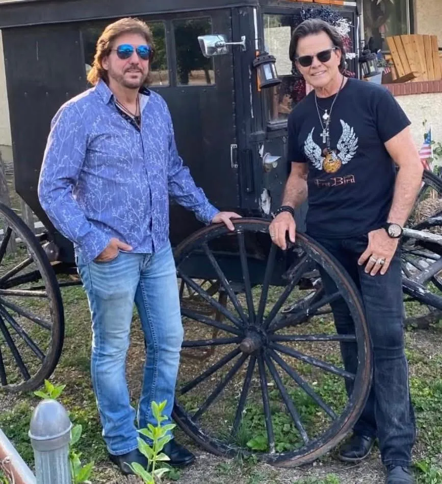 Ed Callison and Darren Hank standing beside an antique carriage wheel