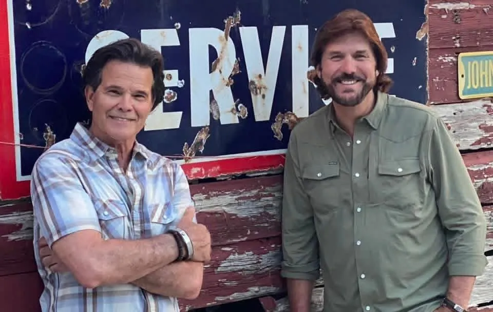 Ed Callison and Darren Hank smiling in front of a vintage service sign