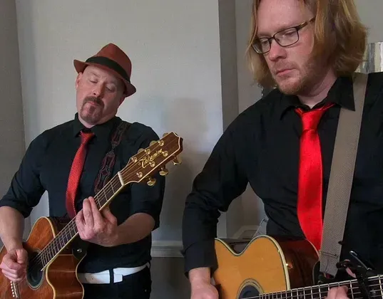 Guitarist Dan Elder playing acoustic guitar alongside vocalist Todd Sarvies during a Hollywood Duo performance