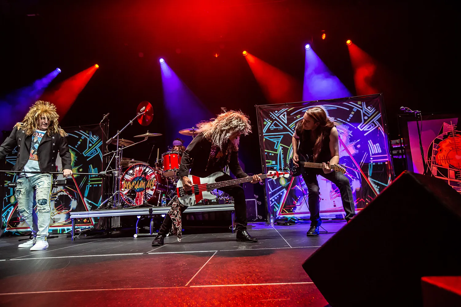 Pyromaniacs, a Def Leppard tribute band, performing on a colorfully lit stage