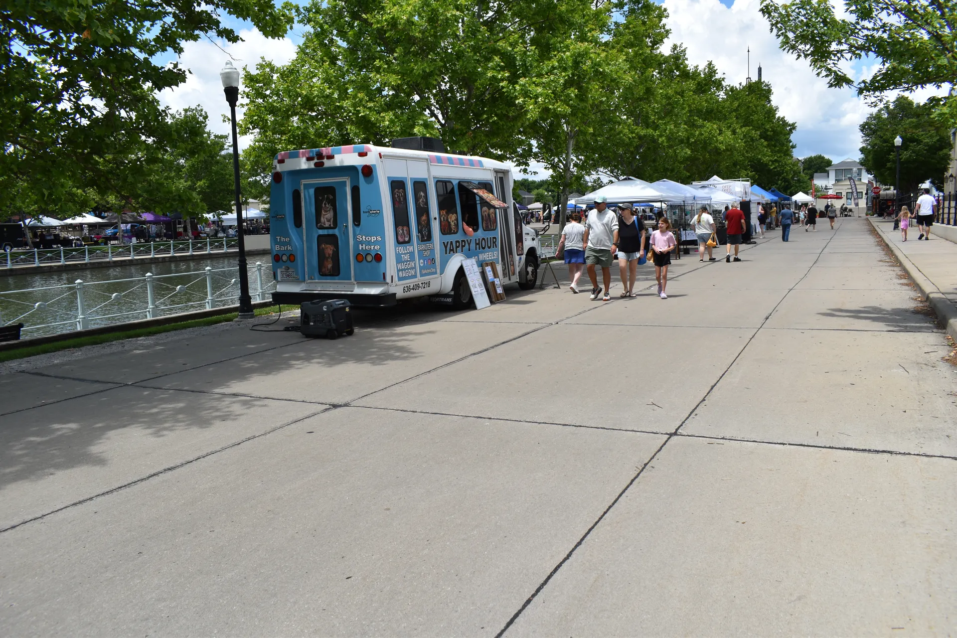 Visitors stroll past a mobile pet shop truck and market booths beside the New Town Grand Canal