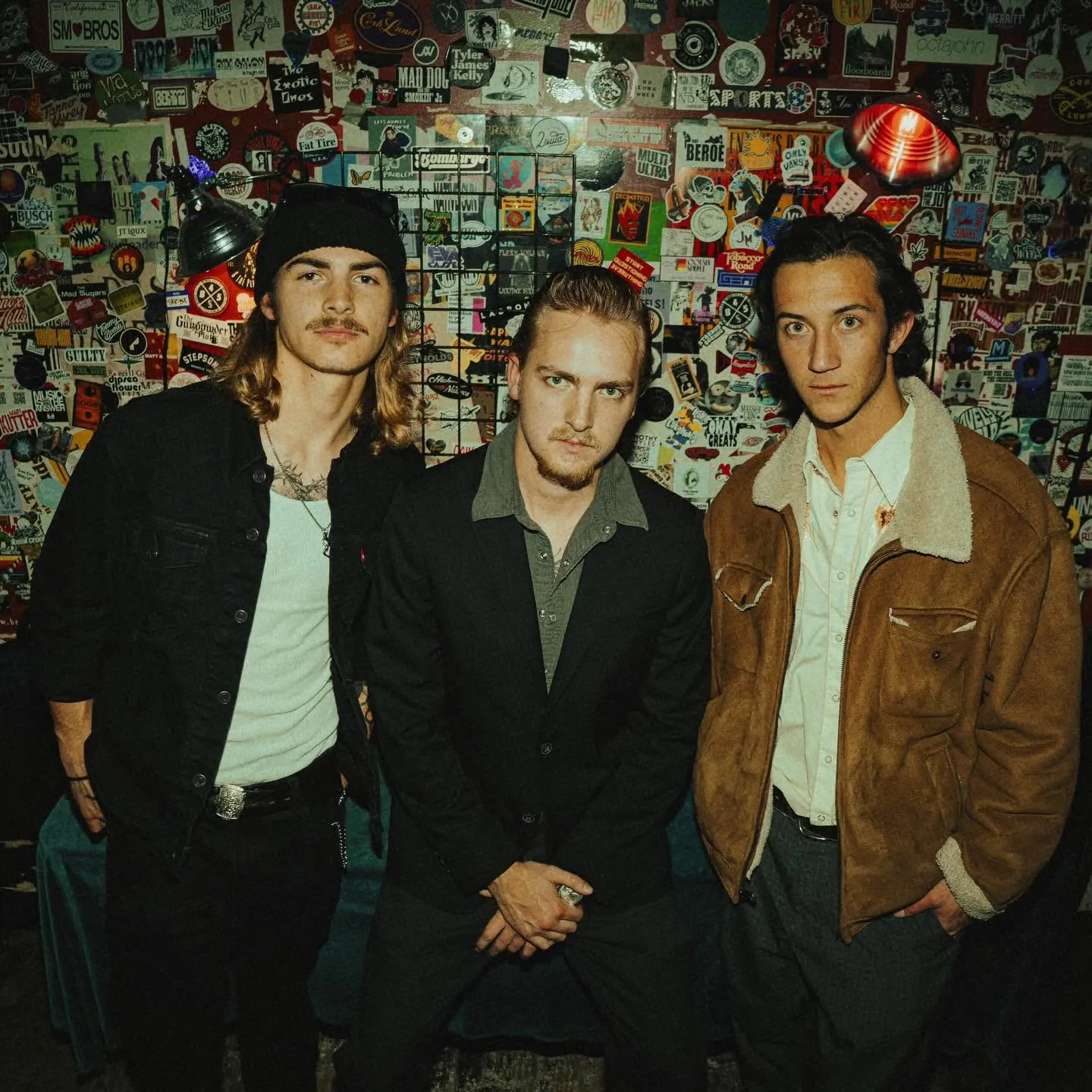The Sea Monks posing backstage against a sticker-covered wall
